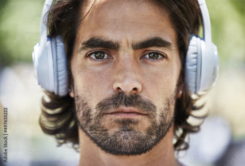 Beast mode activated. Shot of a young man listening to music on his headphones outside in the park.