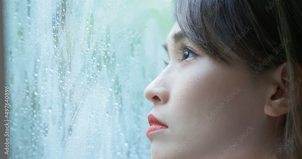 woman look through rainy window