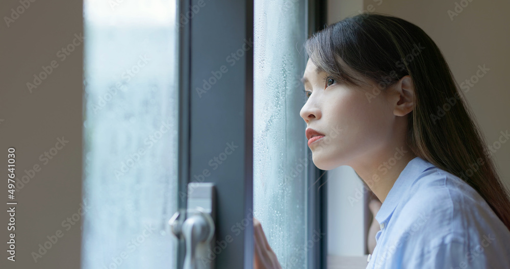 女人透过下雨的窗户看