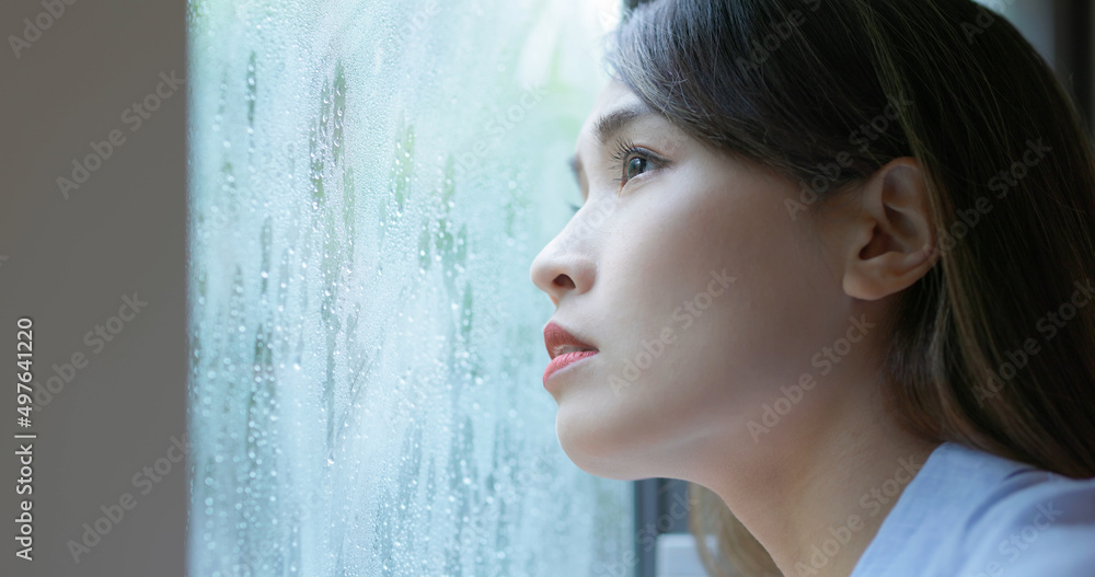 女人透过下雨的窗户看