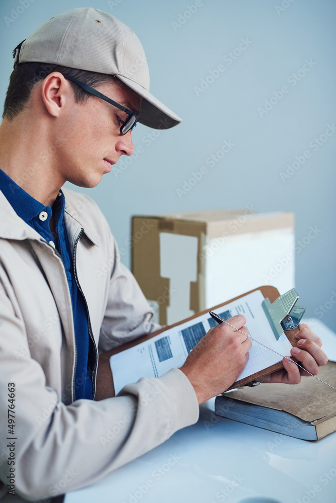 Working hard to get his deliveries out on time. Shot of a courier writing on a clipboard.