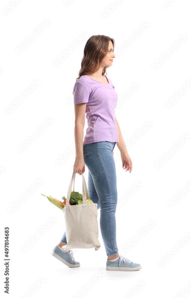 Young woman holding eco bag with fresh vegetables on white background