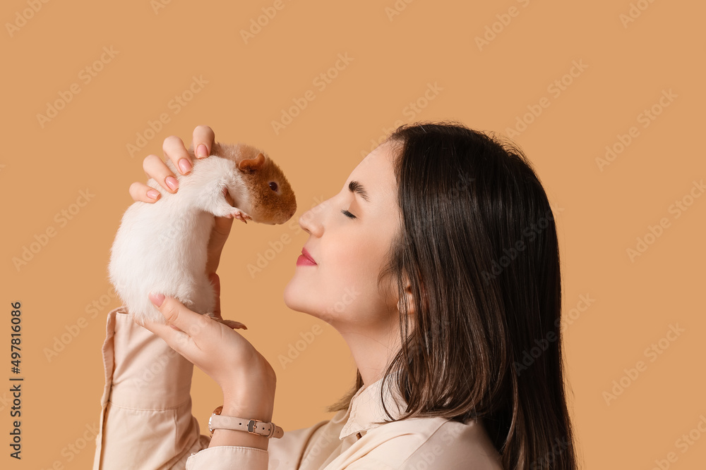 Beautiful young woman with cute guinea pig on color background