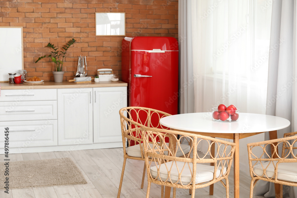 Interior of modern kitchen with stylish refrigerator, dining table and counter