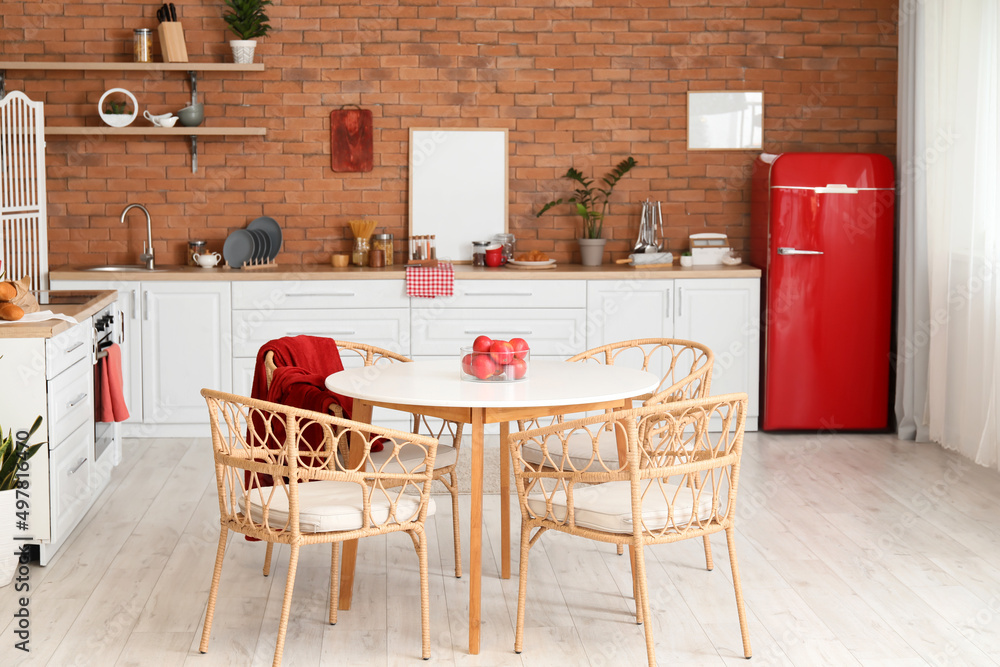 Interior of modern kitchen with stylish refrigerator, dining table and counter