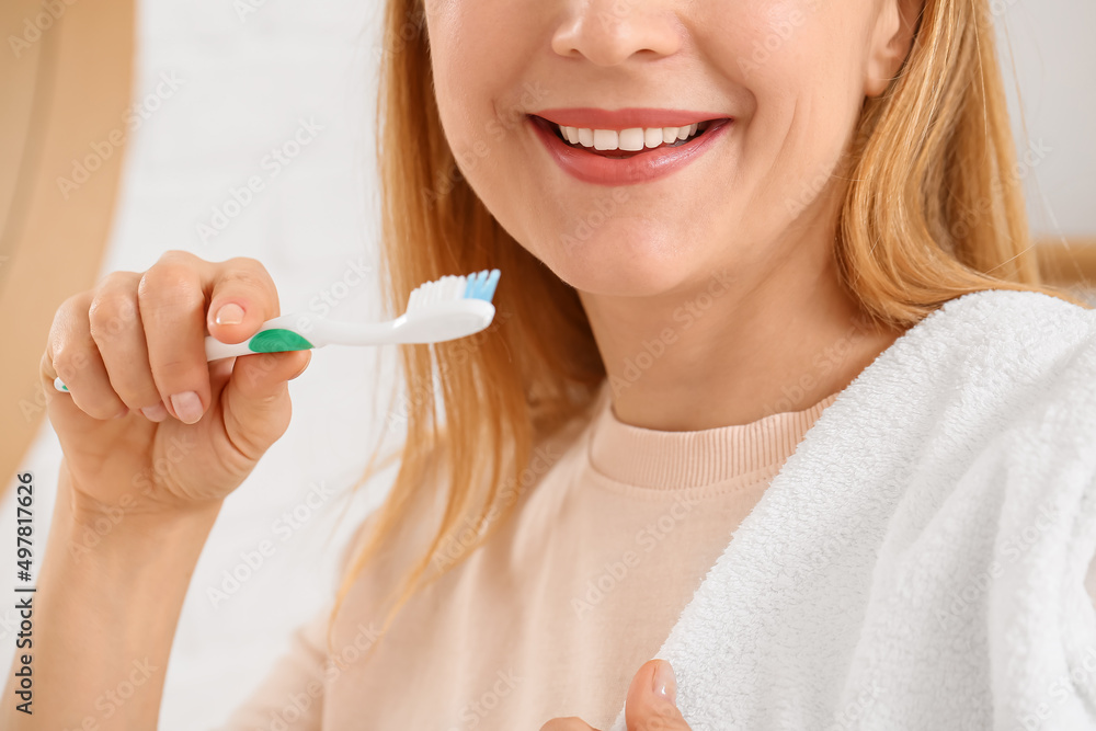 Beautiful mature woman  brushing teeth in bathroom, closeup