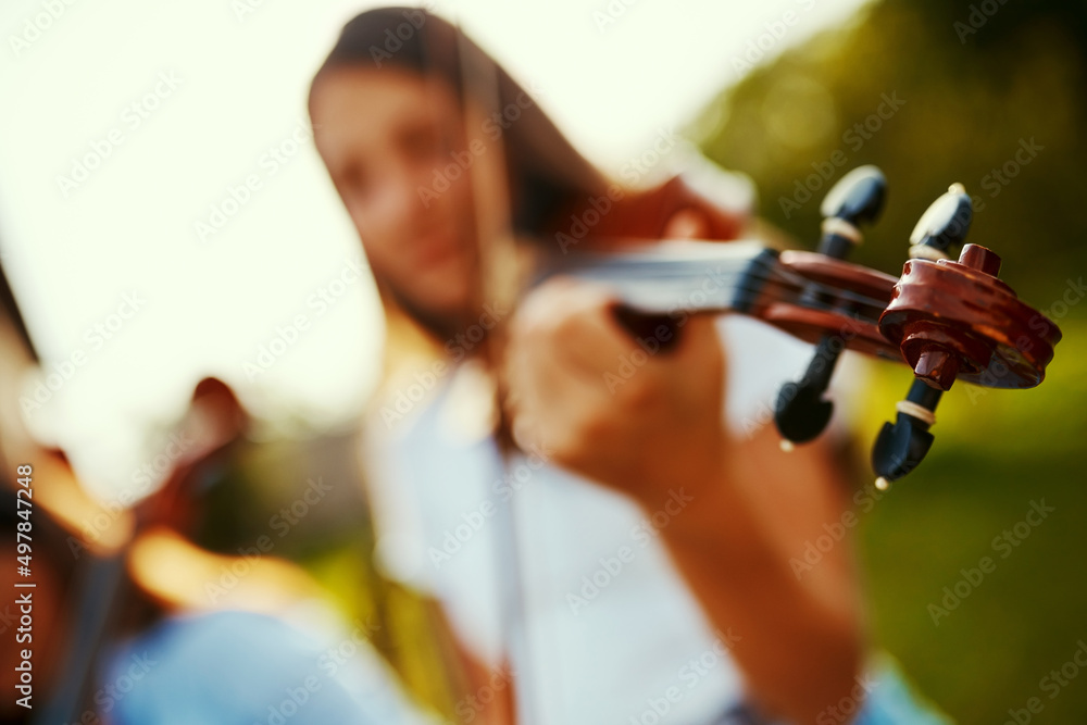 音乐就是生活，这就是为什么我们的心会跳动。一个年轻女孩在户外拉小提琴的裁剪镜头