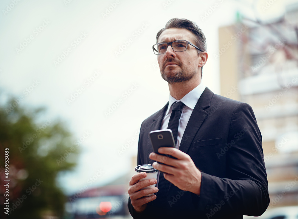 Hes a busy man on the move. Shot of a mature businessman texting on a cellphone while out in the cit