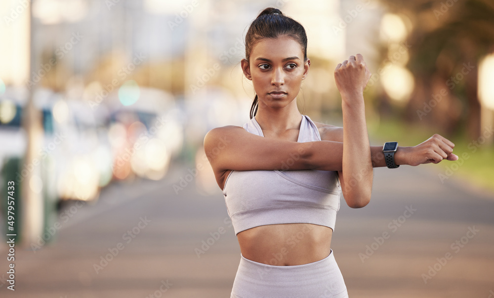 什么挡住了你的去路。一位运动型年轻女子在户外运动时伸展手臂的照片