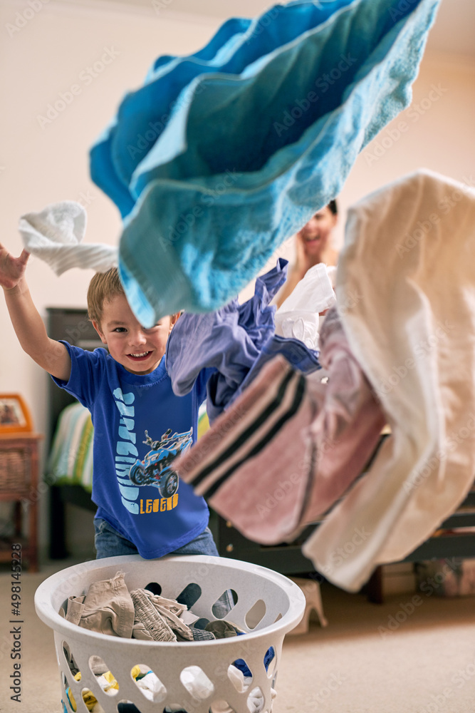 This is so much fun. Portrait of a little boy throwing laundry in the air.