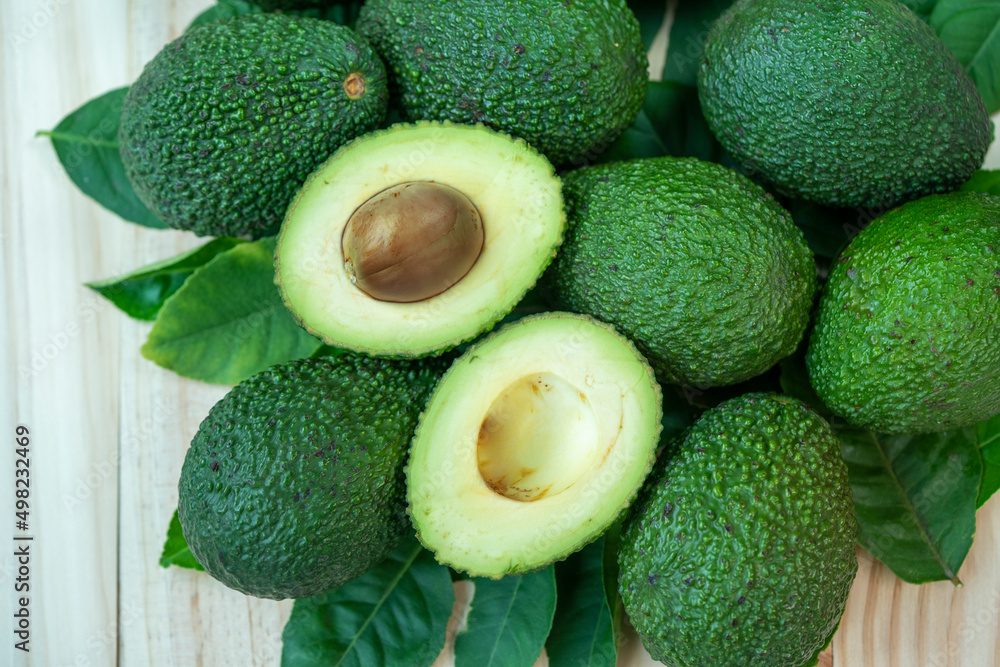 Avocado fruit with leaves on wooden table in garden, Avocado with leaves in wooden background.