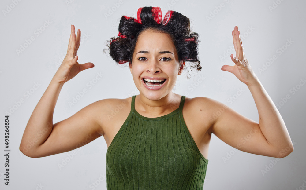 How much longer until I can take this out. Cropped shot of a young woman posing with hair rollers ag