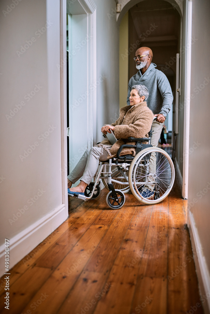 Helping her get around. Cropped shot of a senior man pushing his wheelchair-bound wife through the h