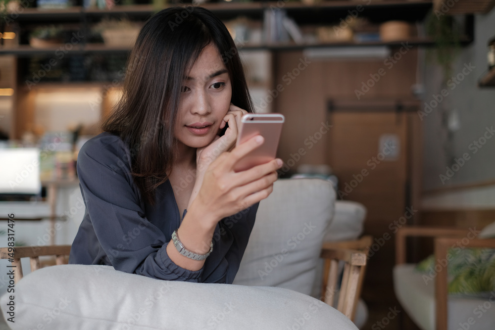 快乐的亚洲女人在咖啡馆用手机或智能手机，咖啡馆有复古色调，手拿