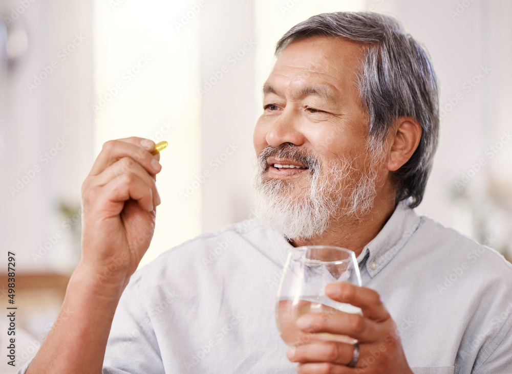 这总是让我感觉好一点。一名老年男子拿着药物和一杯水的照片