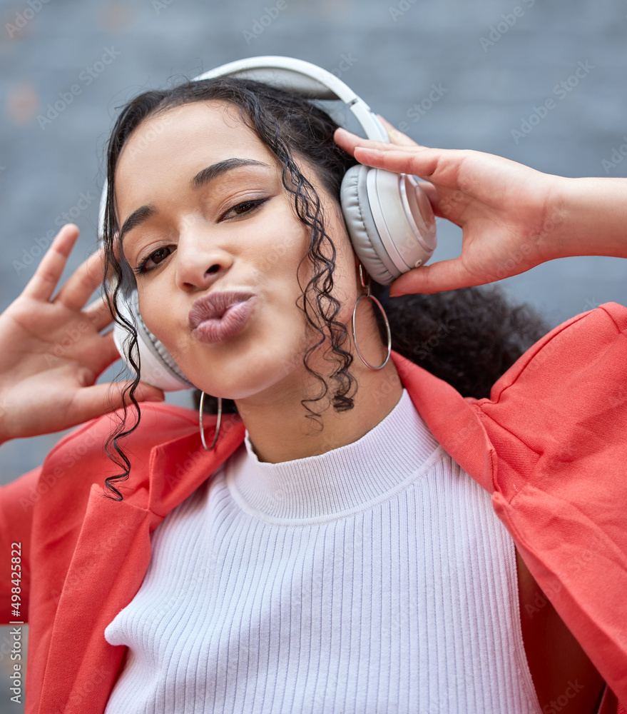 Cheer up and listen to some good music. Shot of a young woman wearing headphones while standing outs