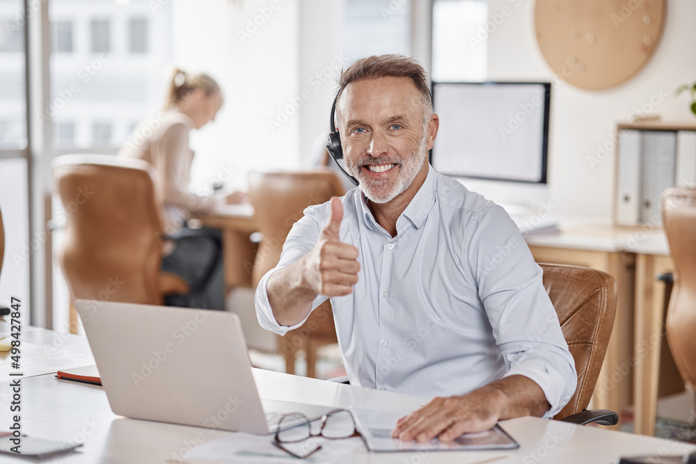 Another day, another happy client. Shot of a mature man using a headset and showing thumbs up in a m