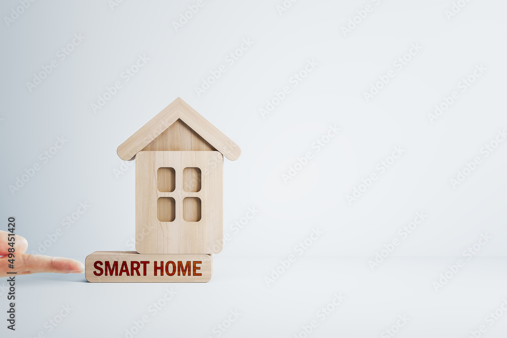 Finger pushing abstract wooden house on white mortgage backdrop with mock up place. Smart home, oan,