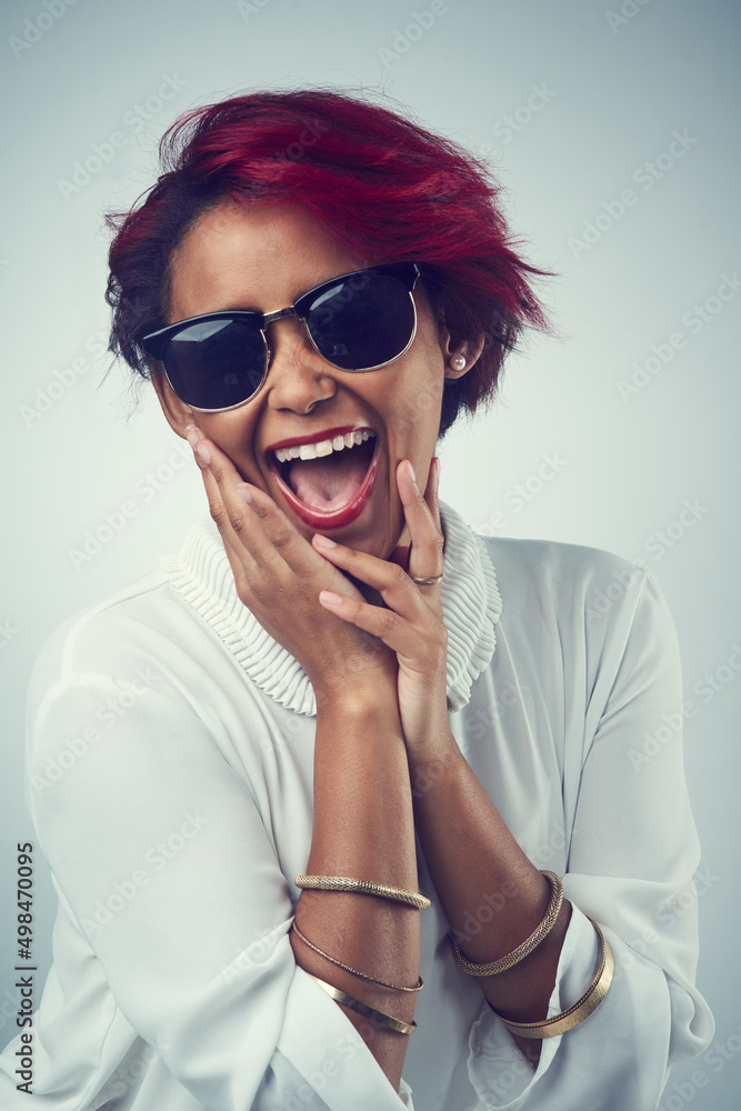 Being happy is a good feeling to feel. Shot of a beautiful young woman wearing sunglasses against a 