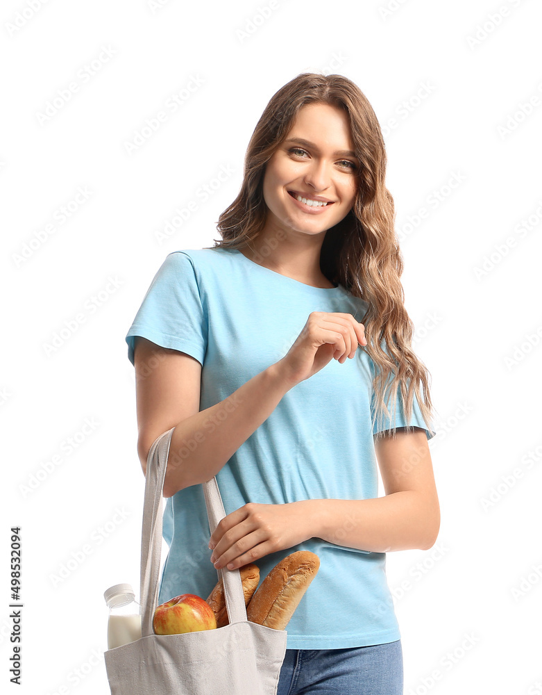 Young woman holding eco bag with food and drink on white background