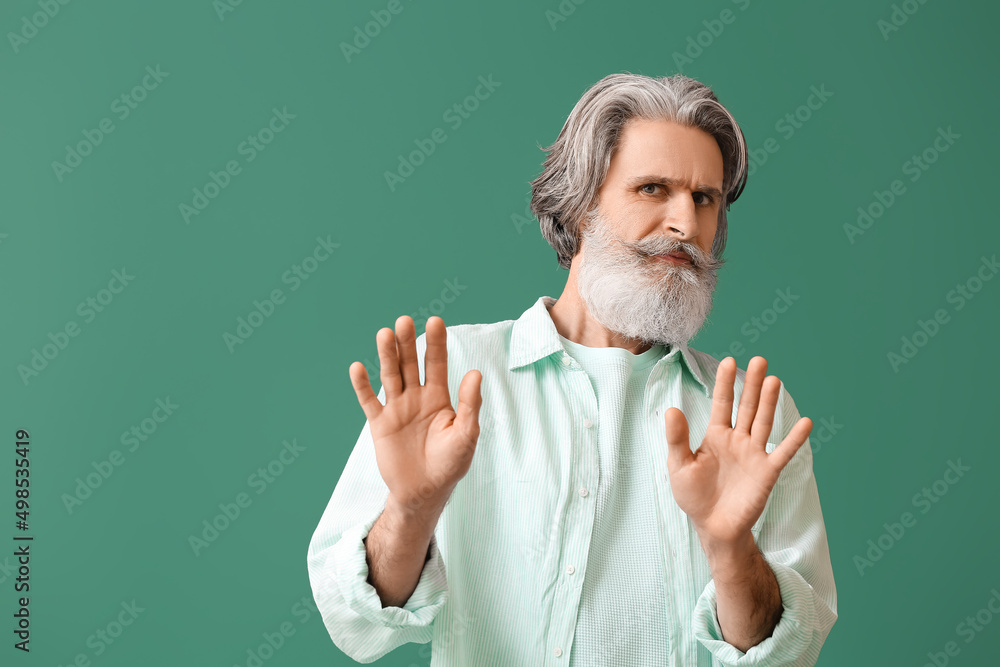 Upset senior man in shirt on green background