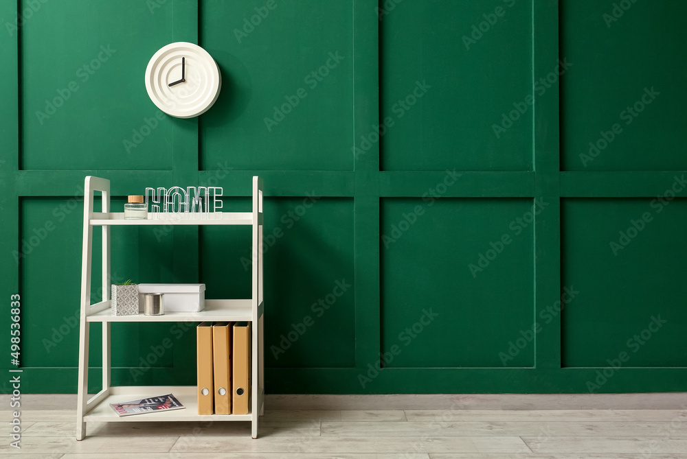 Shelving unit with decor and clock hanging on green wall