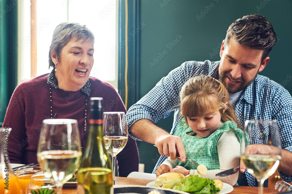 亲爱的，让我帮你。一个快乐的年轻人在做饭时帮女儿切食物的镜头