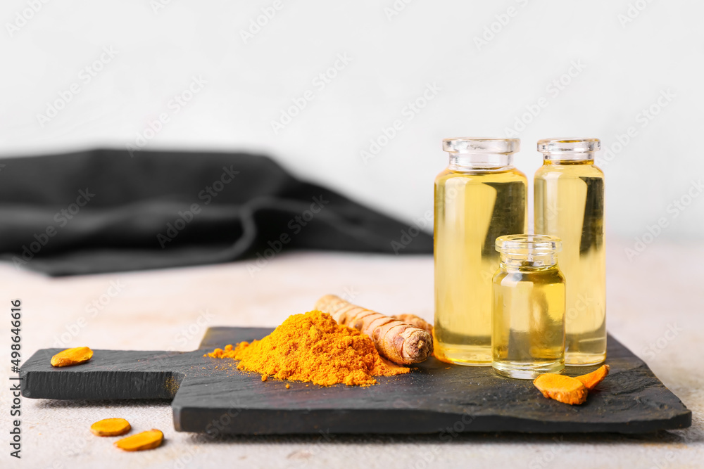 Bottles of oil, turmeric root and powder on light background