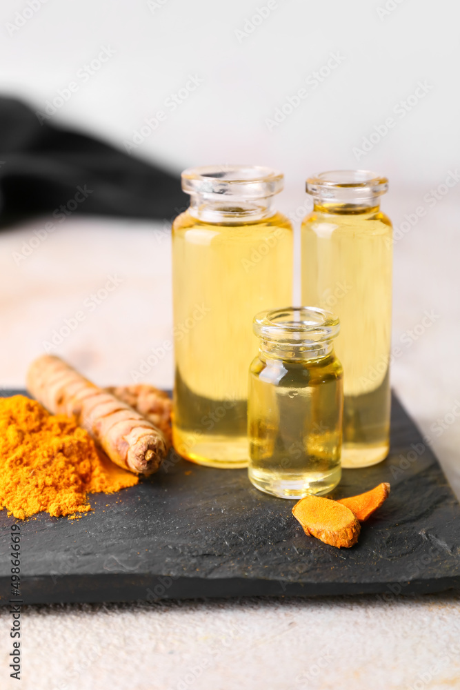 Bottles of oil, turmeric root and powder on light background