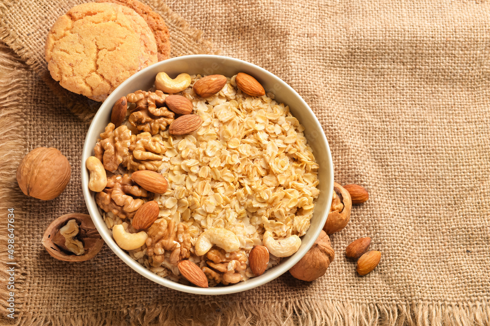 Bowl of healthy oatmeal with nuts on beige background