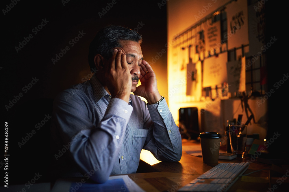 I cant deal with this now. Shot of a mature businessman looking stressed out while working late in a