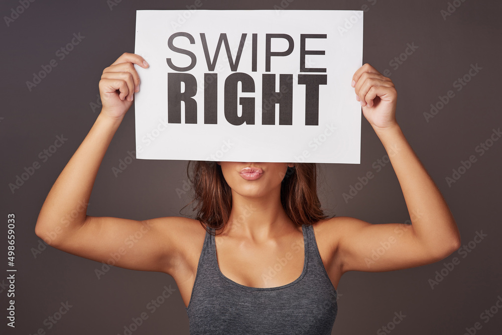 It could be love at first swipe. Studio shot of a young woman holding a sign with swipe right printe