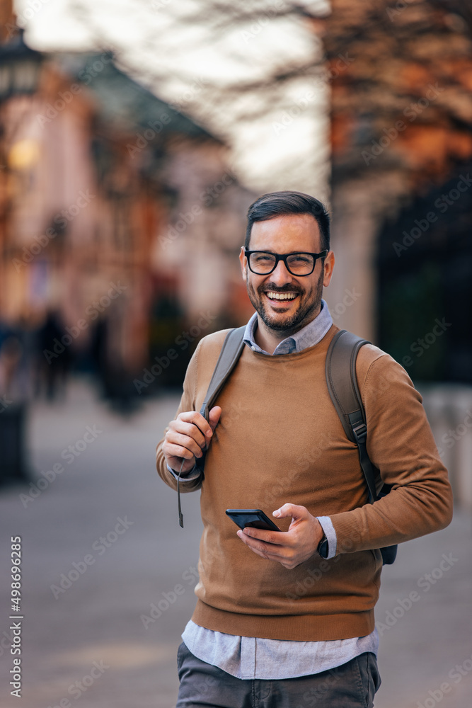 快乐的高加索男子的画像，戴着眼镜，拿着手机，观光。