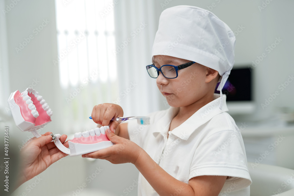 Little doctor in dental uniform. Child playing dentist with instruments.