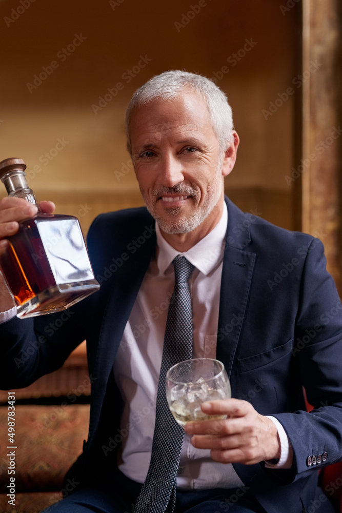 Theres nothing better than a fine whiskey. Portrait of a well-dressed mature man holding a glass and