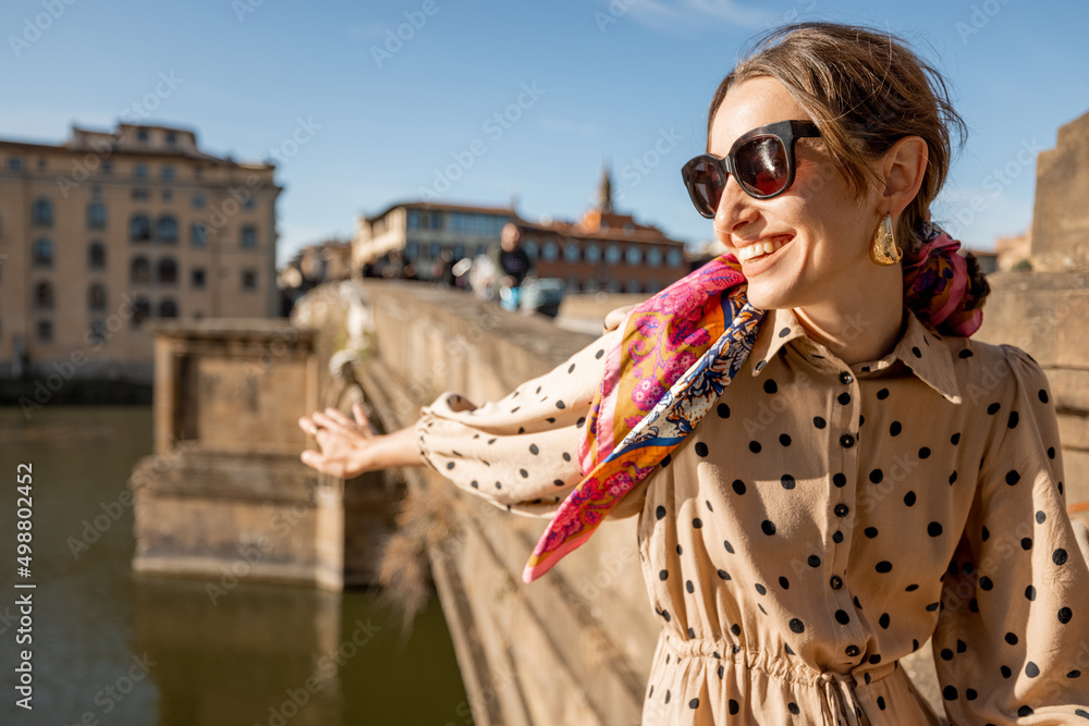 年轻的女人坐在阿诺河畔，在佛罗伦萨的老城区旅行。快乐的旅行者v