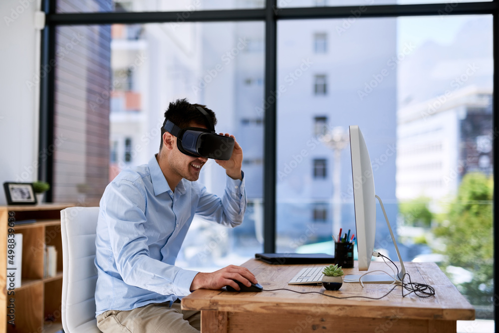 Business just got a little better. Shot of a happy young businessman wearing a virtual reality heads