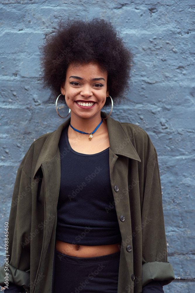 You can boost any mood with just a smile. Portrait of a happy young woman standing against a brick w