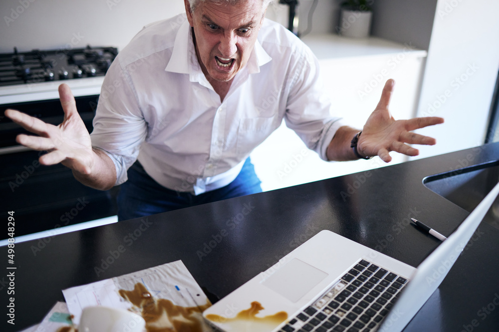 What the heck just happened. Shot of a mature man feeling angry after spilling coffee on his paperwo