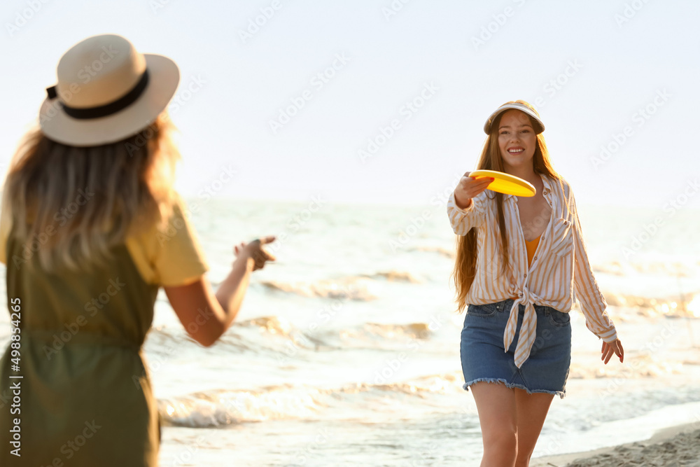 快乐的年轻女子在海边玩飞盘