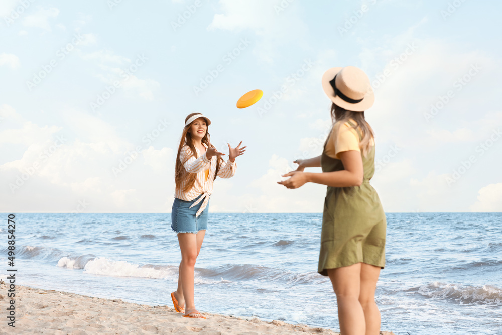 快乐的年轻女子在海边玩飞盘