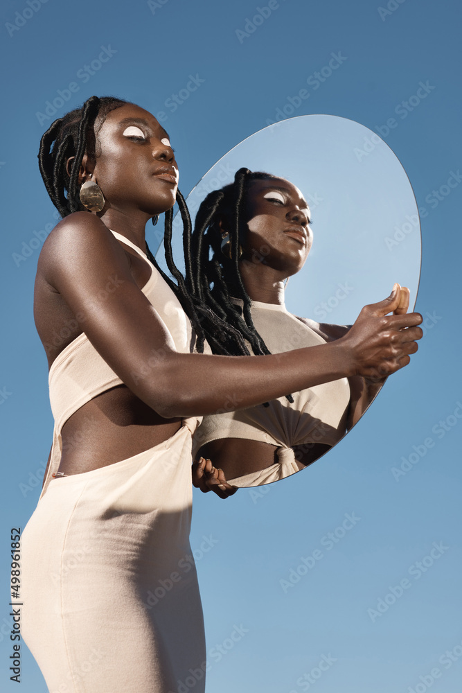 Self reflection brings self acceptance. Shot of an attractive young woman holding a mirror with her 