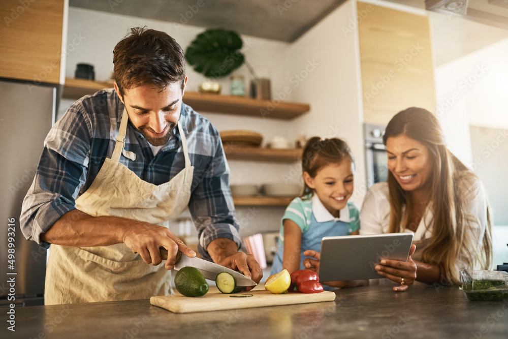 Cooking by their instructions. Shot of two happy parents and their young daughter trying a new recip