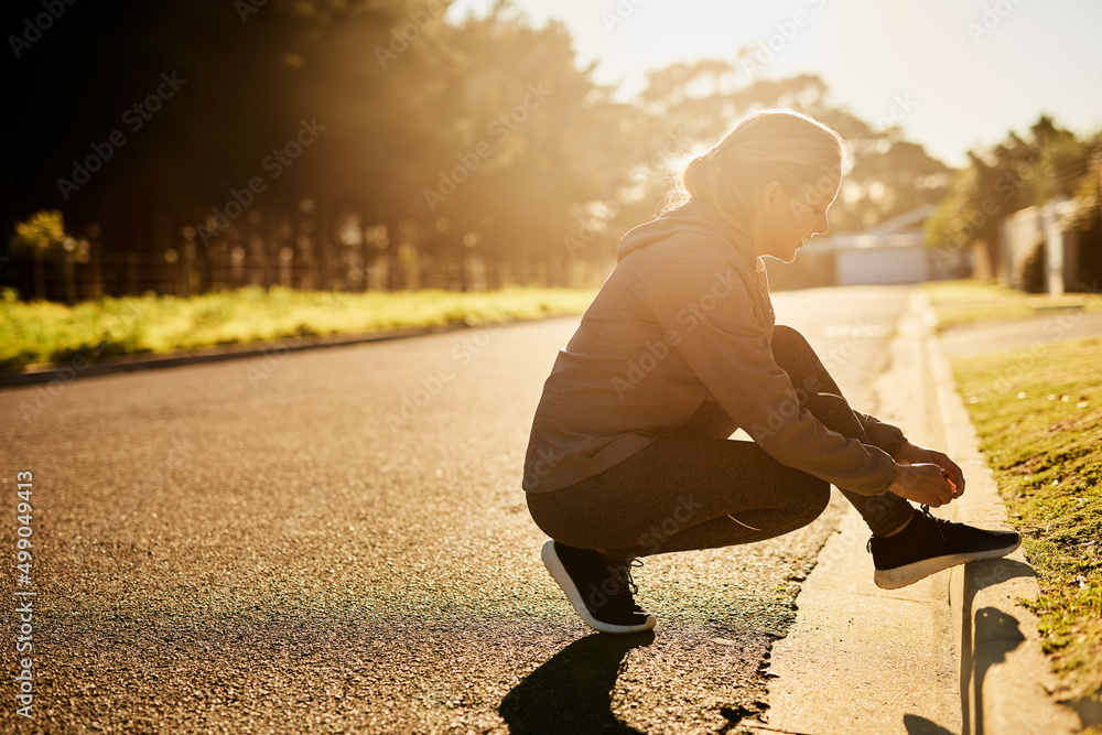 Get up and get out there. Shot of a young woman tying her shoelace before going on a run.