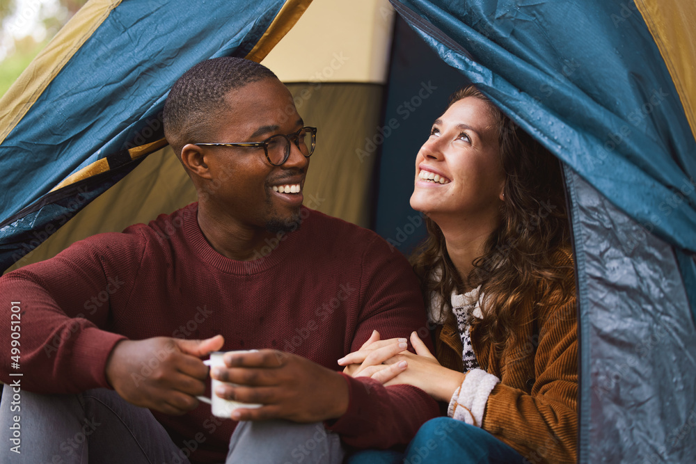 Camping is intents (Pun intended). Shot of a young couple drinking coffee while sitting in their ten