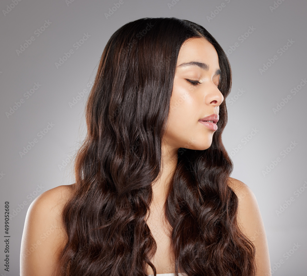 Shes gorgeous. Studio shot of an attractive young woman posing against a grey background.