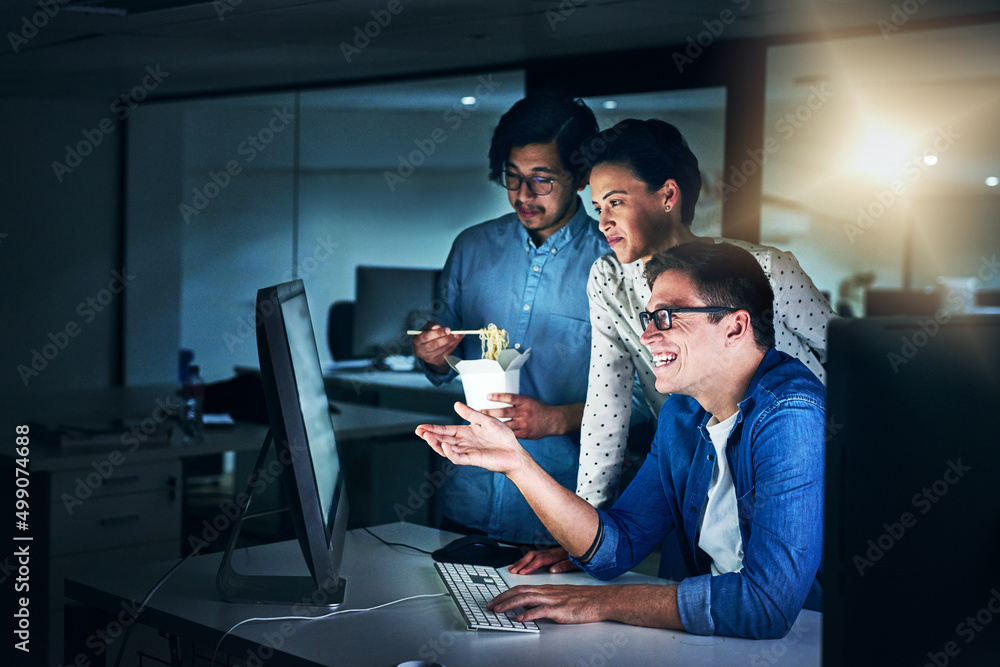 Working the late shift. Shot of a group of programmers working together on a computer in the office 