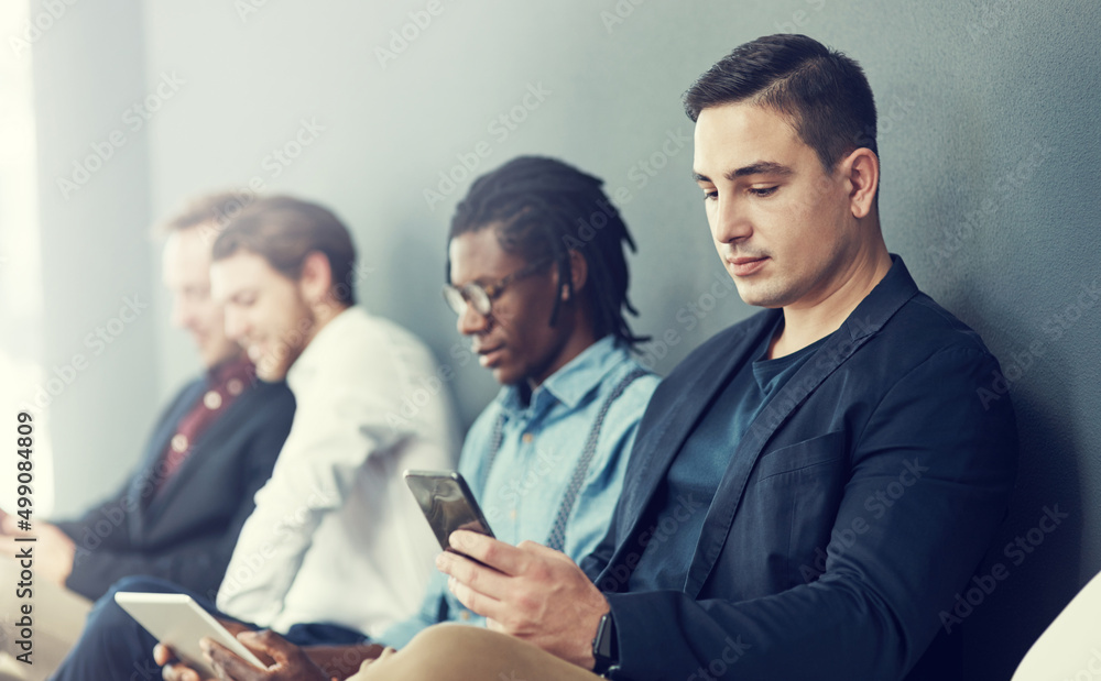 Getting some advice and tips online for the interview. Shot of a group of businessmen using differen