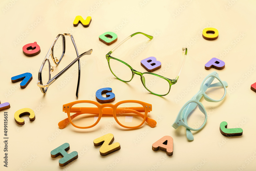 Different eyeglasses and letters on color background