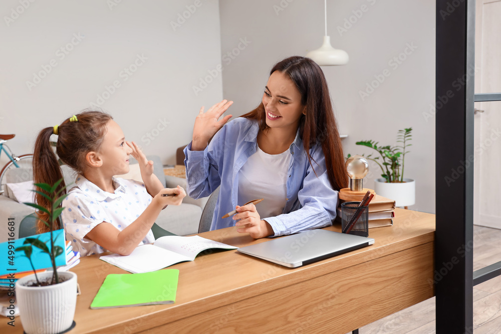 Happy little girl studying with tutor at home